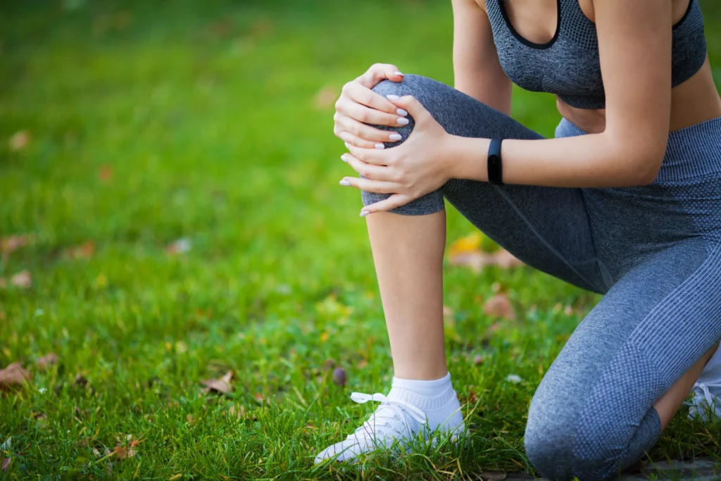 woman crouching on grass holding her knee 2026 03 19 21 48 29 utc