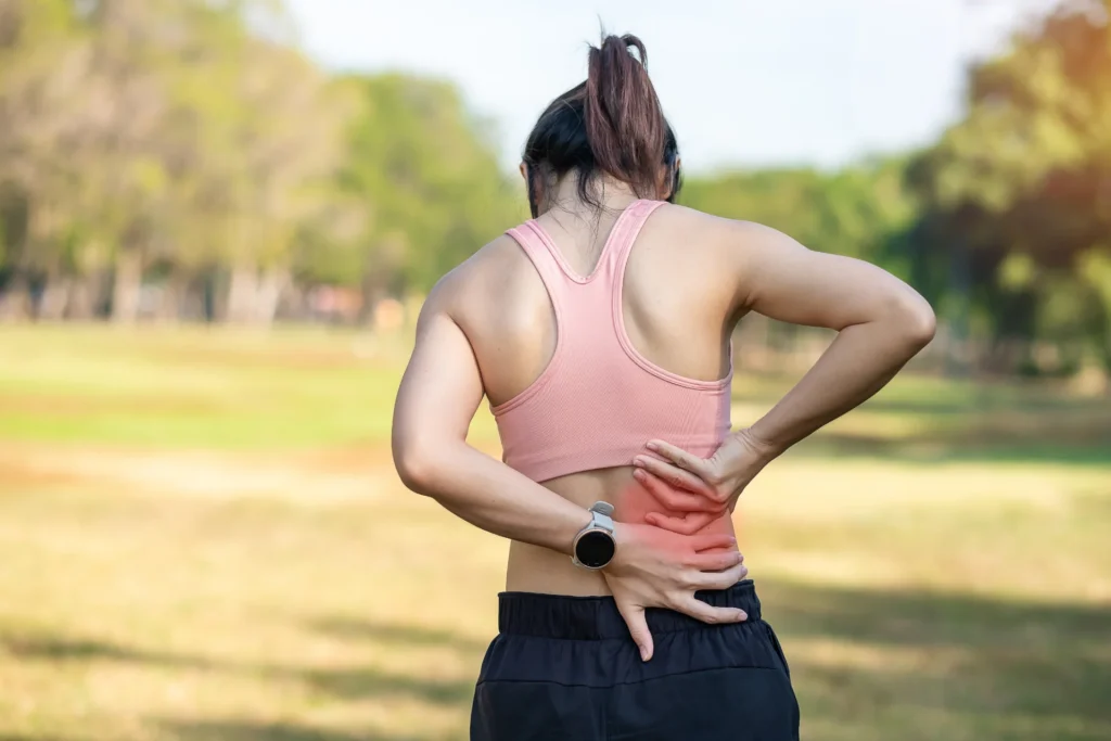woman experiencing back pain in a green field 2026 03 20 00 34 10 utc
