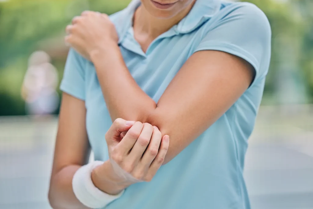 woman massaging her elbow outdoors in daylight 2026 03 25 03 59 31 utc